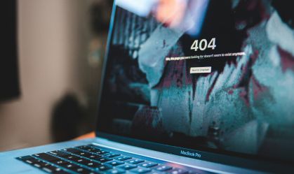 A fotografia apresenta a frente da tela de um MacBook, da Apple, com uma página escrita "erro 404".