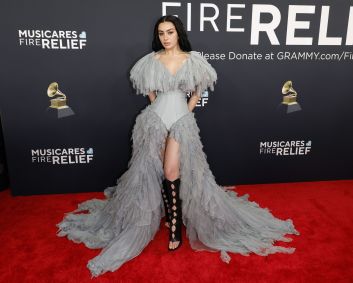Charli XCX uniu um corpete clássico com mangas e uma saia de babados cinzas, combinando com uma bota preta até os joelhos