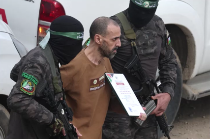 Eli Sharabi é escoltado por homens armados e encapuzados do Hamas durante liberação