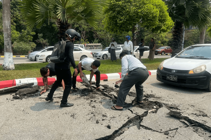 Motoristas recolhem pedaços de uma estrada danificada na capital de Mianmar, Naypyidaw, após o terremoto. • Getty Images