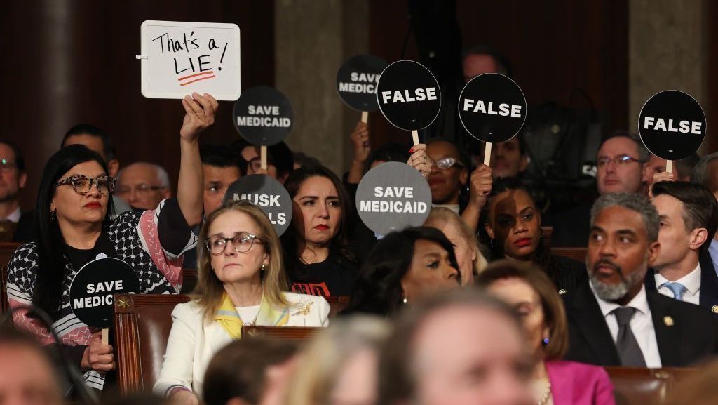 Democratas seguram cartazes de protesto enquanto o presidente dos Estados Unidos, Donald Trump, discursa em uma sessão conjunta do Congresso em 04 de março de 2025