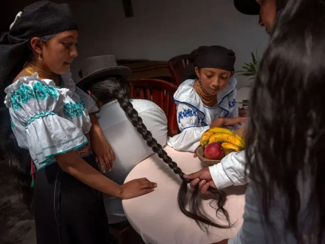 RUMInawi Cachimuel trança o cabelo de seu filho, Dylan, enquanto suas filhas assistem • Irina Werning