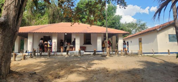 Fachada do Museu de Rochas e Minerais, no Rio. O imóvel é branco e tem o teto levemente rosado. Há um grupo de pessoas em frente à construção.