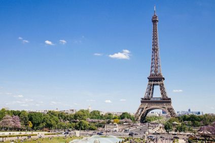 Vista da Torre Eiffel, em Paris. Ela é cercada por árvores.
