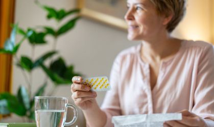 A smiling woman is relieved to get her HRT pills