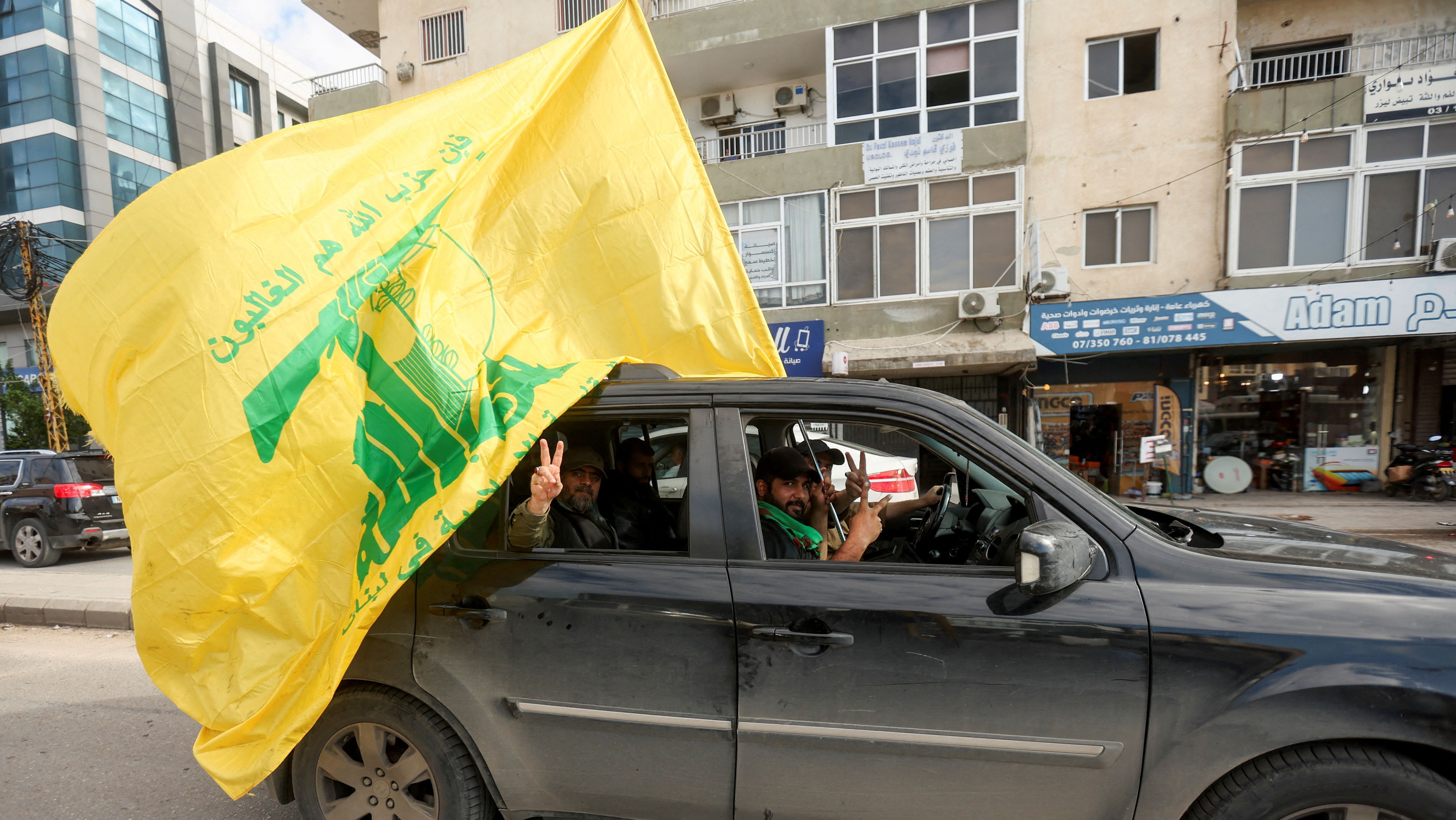 Um homem gesticula enquanto segura bandeira do Hezbollah no segundo dia do cessar-fogo entre Israel e o grupo apoiado pelo Irã em Tiro, no sul do Líbano