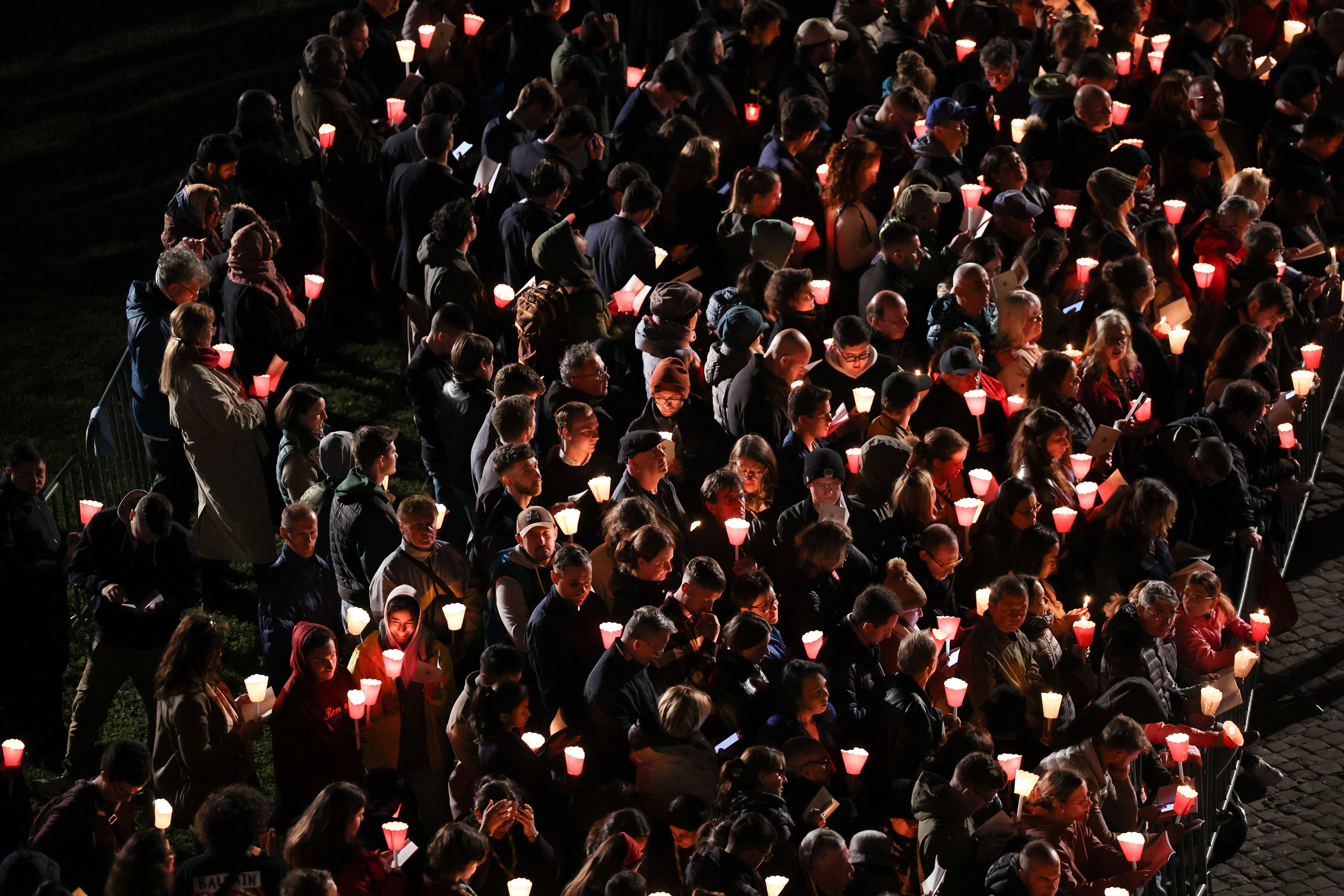 Pessoas carregam velas do lado de fora do Coliseu em Roma durante Via Crúcis