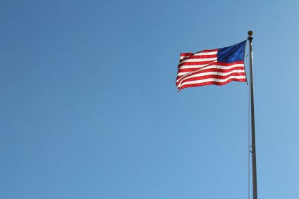 Bandeira dos Estados Unidos hasteada. Ela é vermelha, branca e azul.