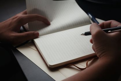 Pessoa escrevendo em caderno