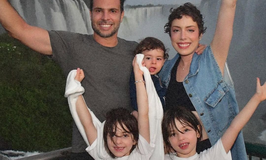 Fabiana Justus visitando Cataratas do Iguaçu com o marido e os três filhos. Eles estão sorrindo e com os braços erguidos para cima