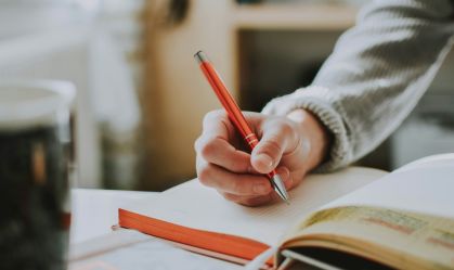 Jovem estudando. Ele está fazendo anotações no caderno