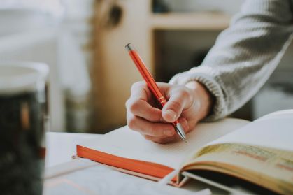 Jovem estudando. Ele está fazendo anotações no caderno