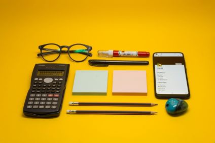 Material escolar em cima de mesa e fundo amarelo
