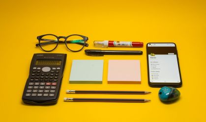 Material escolar em cima de mesa e fundo amarelo