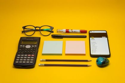 Material escolar em cima de mesa e fundo amarelo