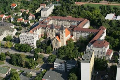 Prédio da Universidade de Pécs, uma das mais antigas na Europa. O local é cercado por árvores.