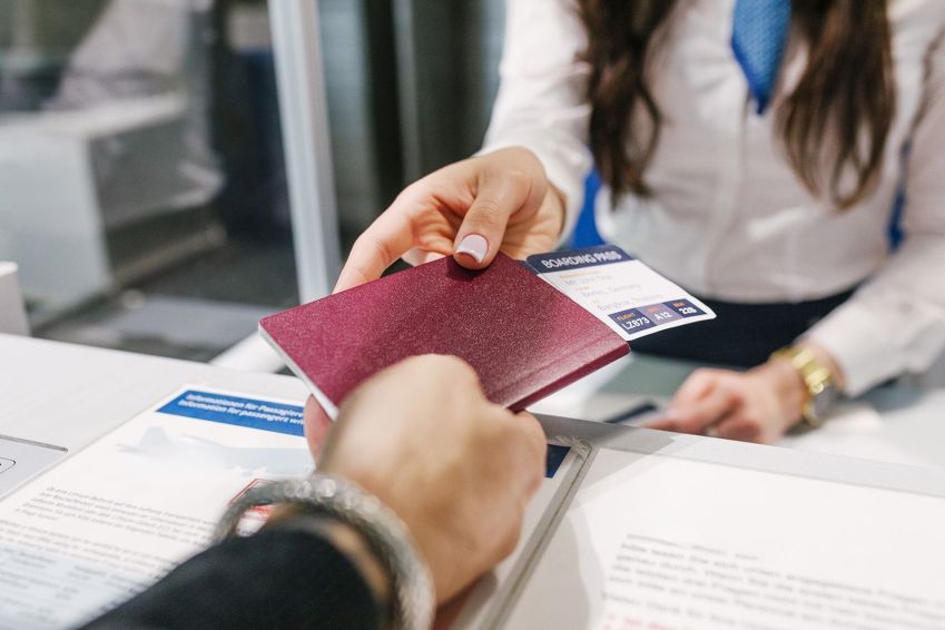 Passaporte e cartão de embarque entregues a uma funcionária do aeroporto enquanto um homem faz o check-in para seu voo. • Hinterhaus Productions/Digital Vision/Getty Images via CNN Newsource