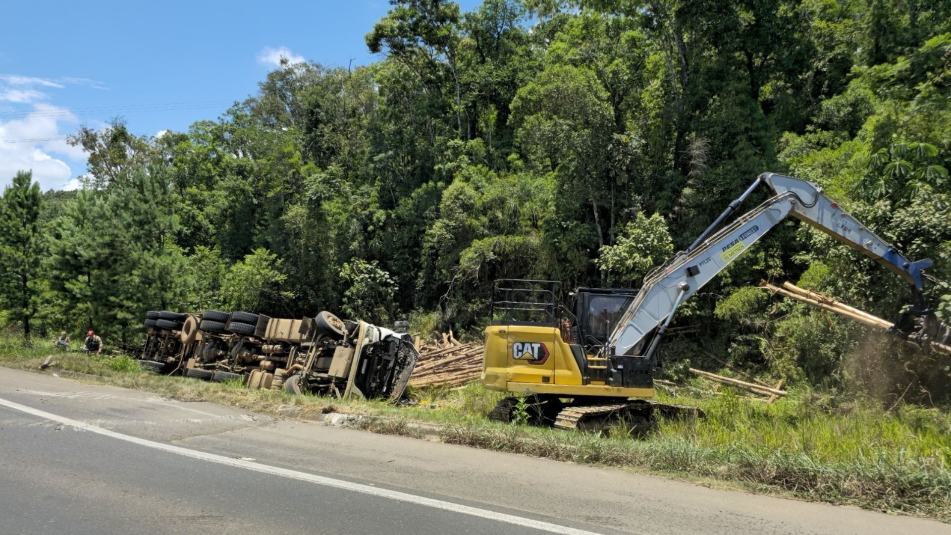 Carreta com aproximadamente 35 toneladas de toras de madeira tomba em cima de carro • Divulgação/PCPR