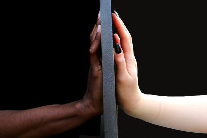 Duas mãos. Uma é de uma pessoa negra e a outra de uma pessoa branca