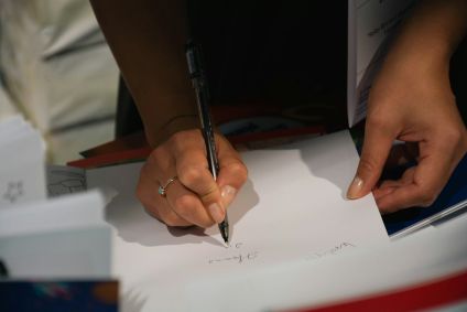 Pessoa escrevendo em folha de papel
