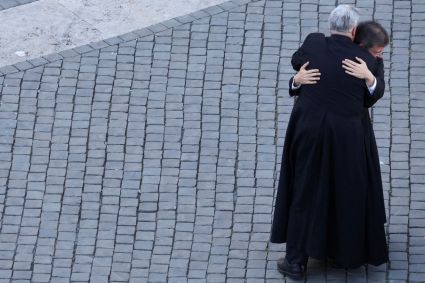 Sacerdotes se abraçam enquanto reagem à fumaça branca que sai da chaminé da Capela Sistina, indicando que um novo papa foi eleito, no Vaticano, em 8 de maio de 2025.