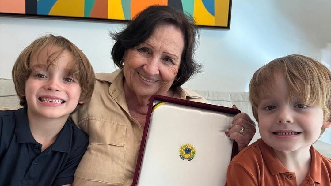Ela está segurando a condecoração entregue pelo presidente Lula à família do artista, a Ordem do Mérito Cultural, reconhecimento mais importante da cultura brasileira