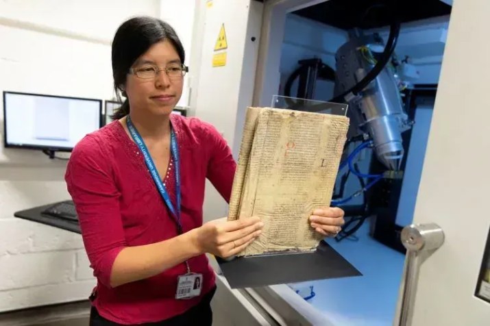 Dra. Irène Fabry-Tehranchi segurando o raro manuscrito antes de inseri-lo no scanner de microtomografia computadorizada do Departamento de Zoologia da Universidade de Cambridge • Universidade de Cambridge