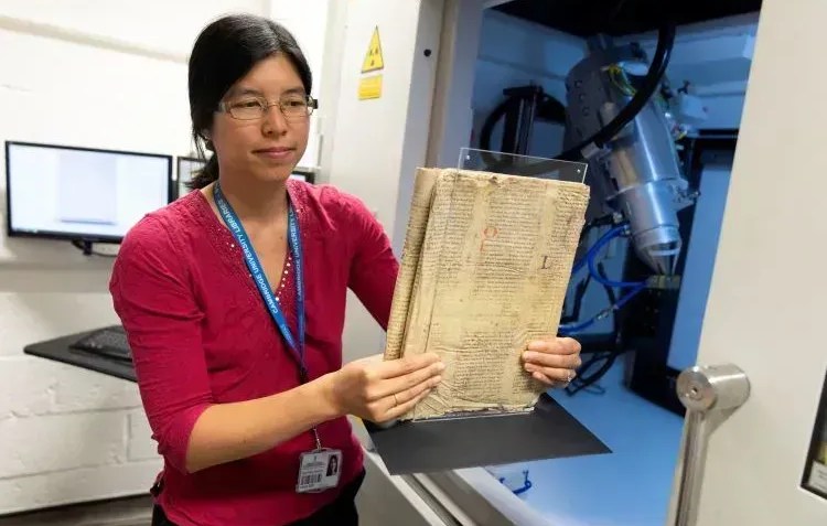 Dra. Irène Fabry-Tehranchi segurando o raro manuscrito antes de inseri-lo no scanner de microtomografia computadorizada do Departamento de Zoologia da Universidade de Cambridge • Universidade de Cambridge