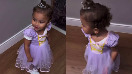 No vídeo, a pequena está usando um vestido roxo e uma coroa apoiada em seu pequeno coque no cabelo