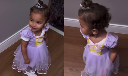 No vídeo, a pequena está usando um vestido roxo e uma coroa apoiada em seu pequeno coque no cabelo
