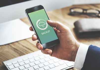 A imagem apresenta um pessoa segurando um smartphone que apresenta uma tela de backup, para limpar a memória do celular.