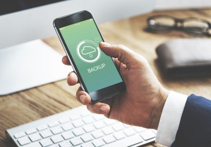 A imagem apresenta um pessoa segurando um smartphone que apresenta uma tela de backup, para limpar a memória do celular.