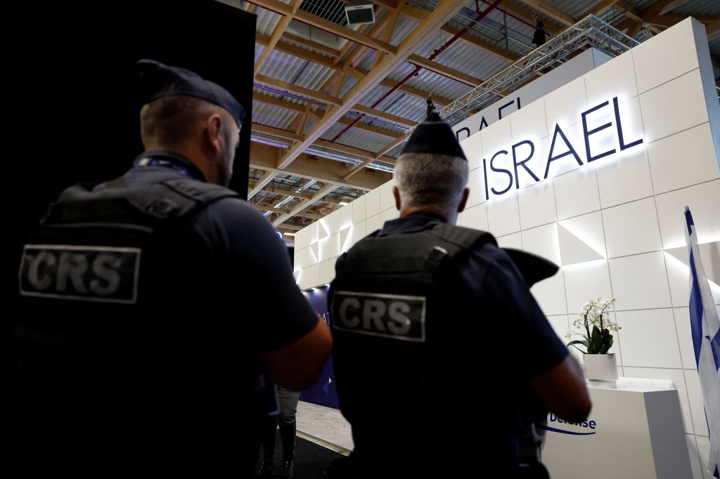 A polícia francesa passa pelo estande do Ministério da Defesa de Israel, que permanece aberto sob proteção, já que os quatro principais estandes de empresas israelenses no Paris Airshow foram fechados pelos organizadores durante o 55º Paris Air Show no Aeroporto Le Bourget, perto de Paris, França, em 16 de junho de 2025.