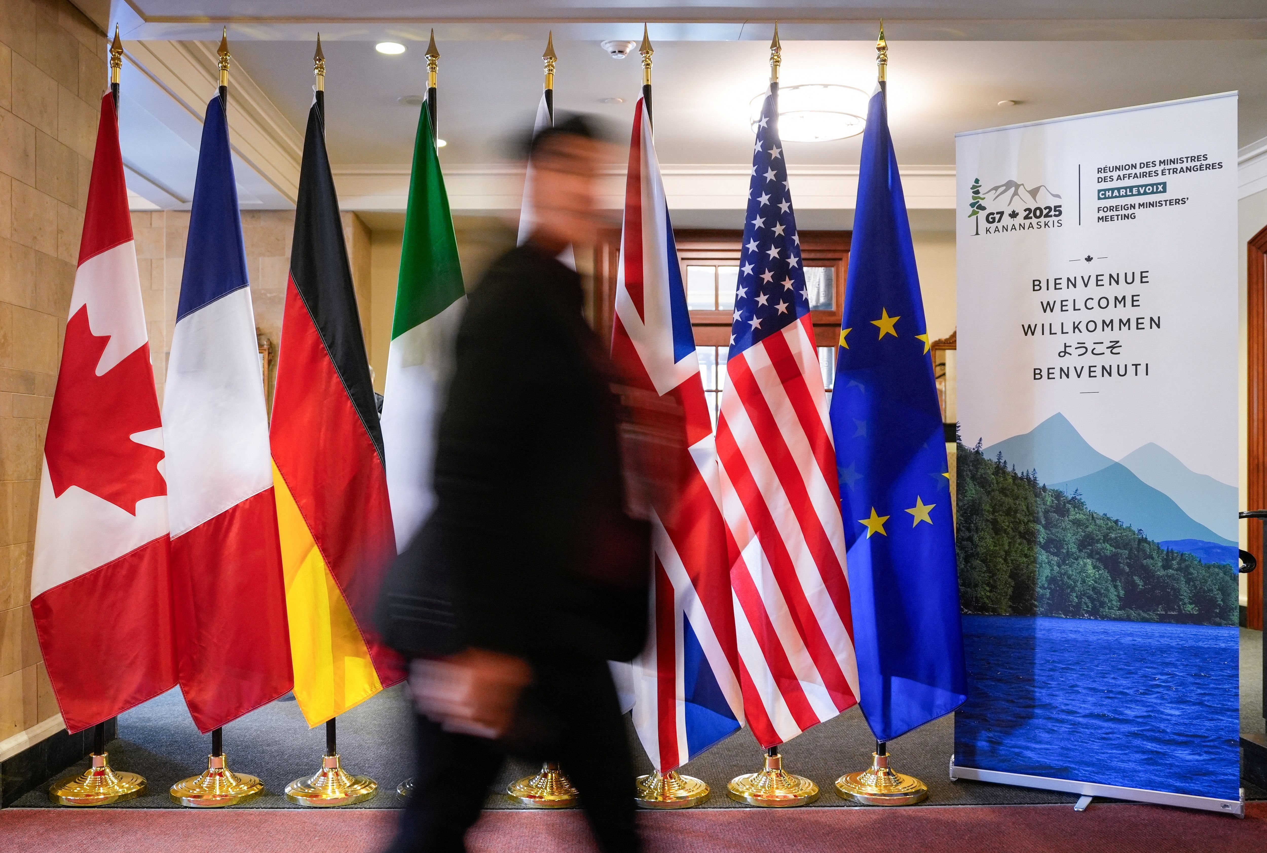 Homem passa em frente às bandeiras dos membros do G7