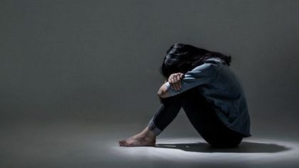 Garota triste em um canto escuro com a cabeça baixa
