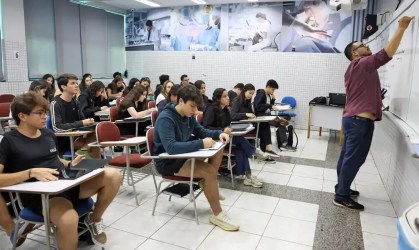 Alunos na sala de aula; professor escrevendo na lousa