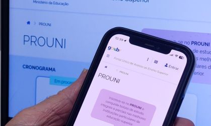 Mão segura celular na página do Prouni