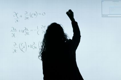 Professora escrevendo contas em lousa