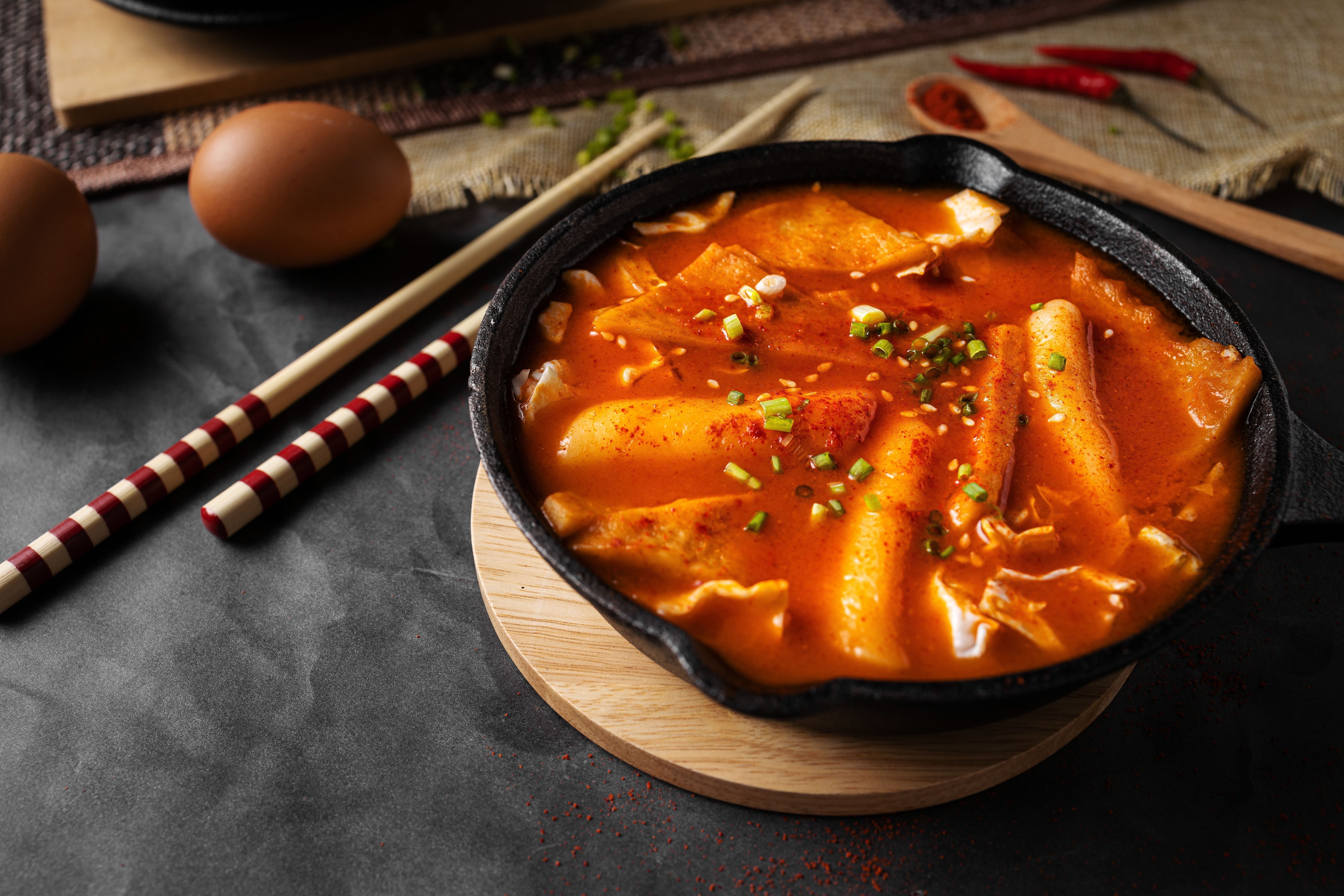 Horizontal shot of a soup in black bowl and some eggs and wooden chopsticks