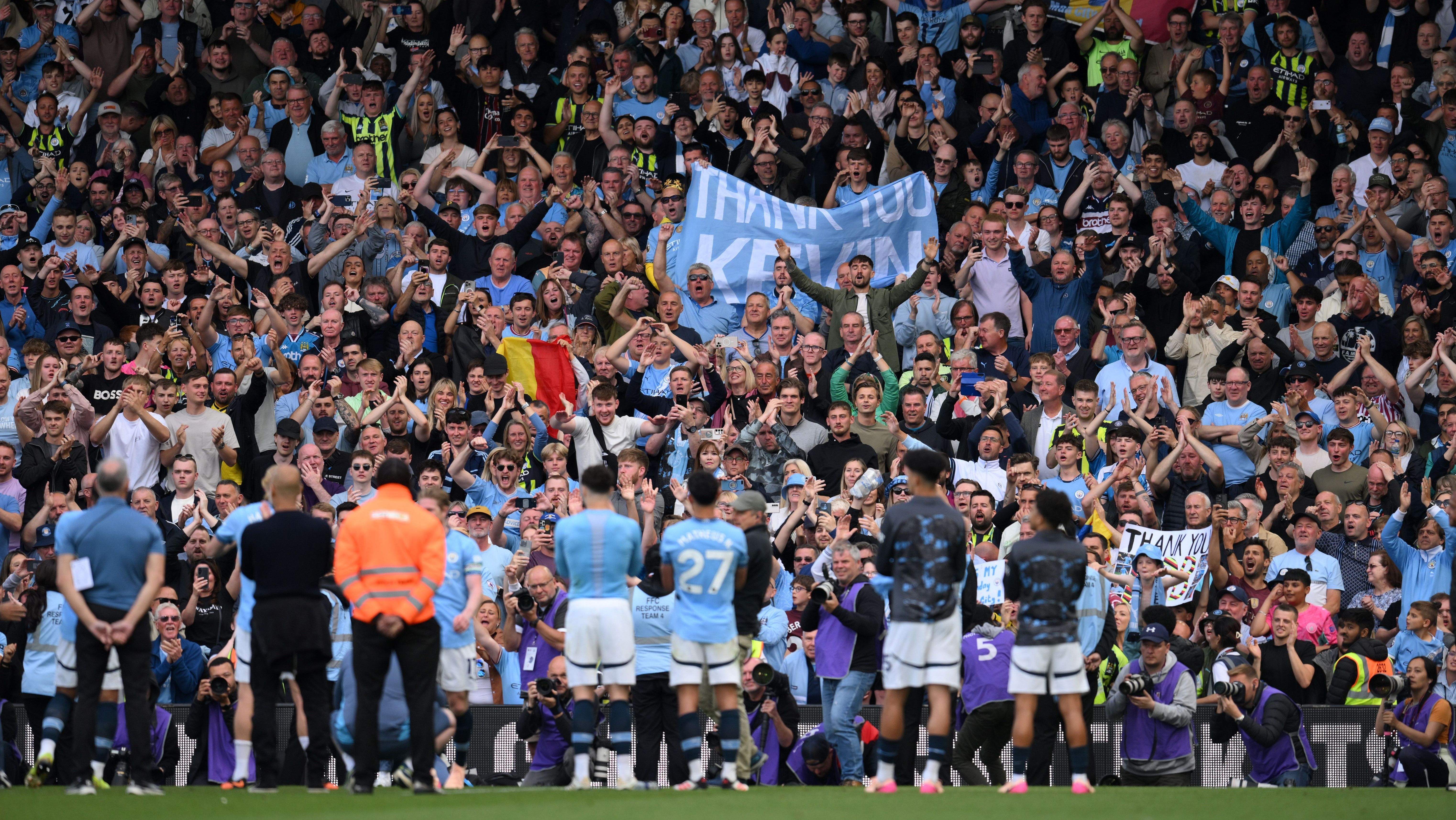 Torcedores do Manchester City aplaudem o time e exibem uma faixa agradecendo a Kevin De Bruyne após sua última partida