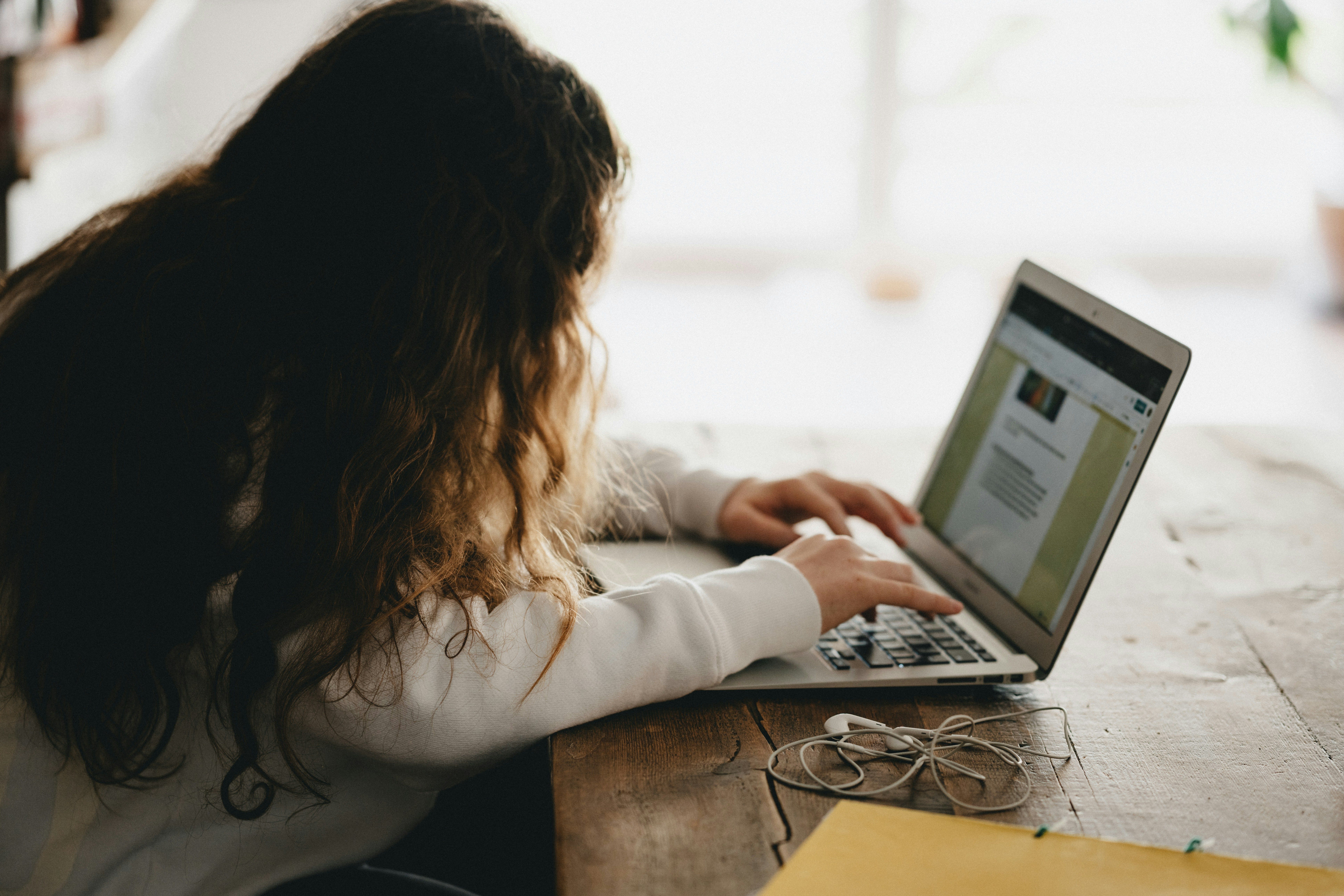 Na imagem, mulher com postura errada se inclina em direção a notebook.