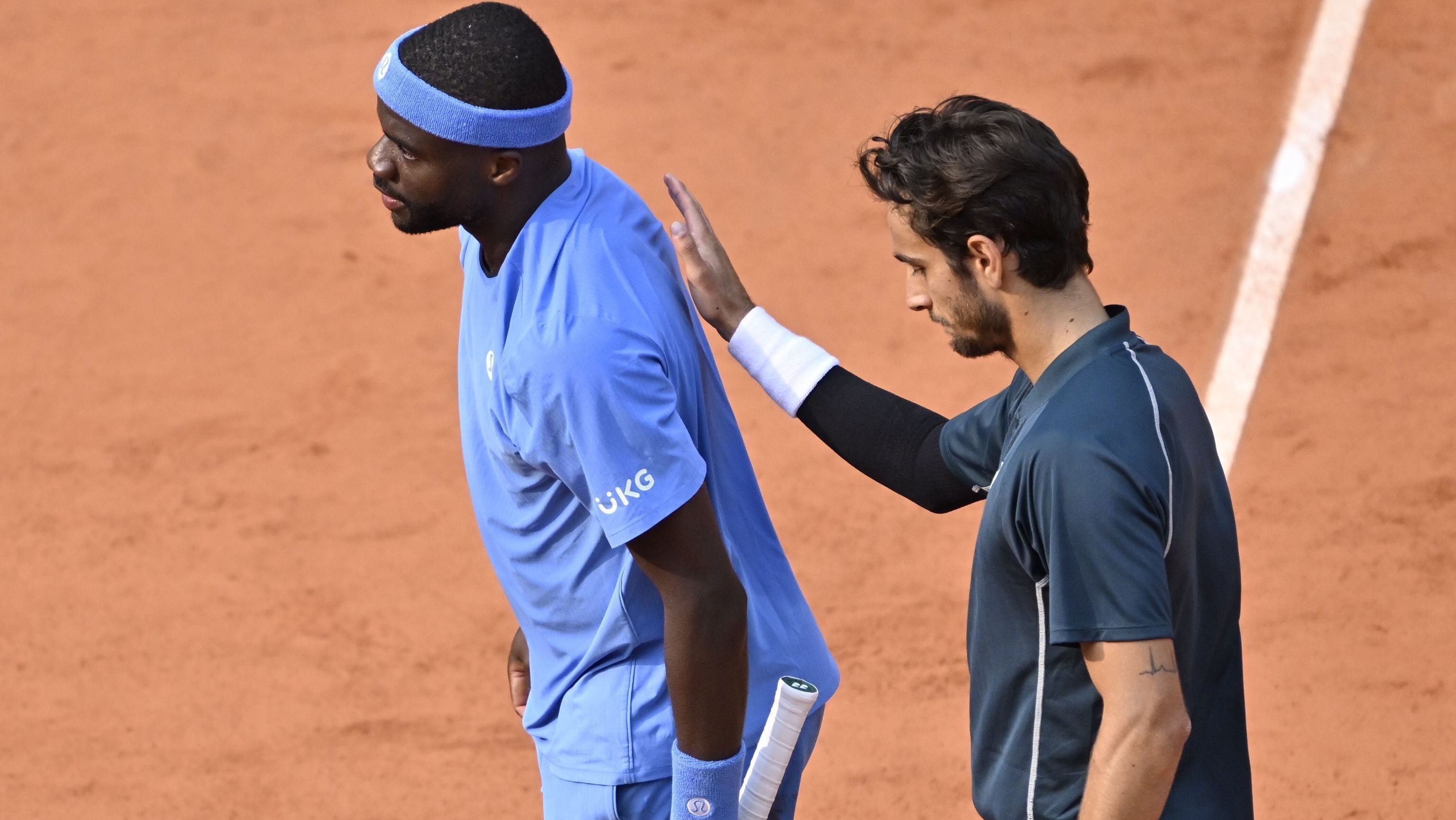 Lorenzo Musetti (de verde) consola Frances Tiafoe após o duelo entre eles pelas quartas de final de Roland Garros