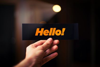 Mão segundo uma placa escrito "hello" (olá em inglês)