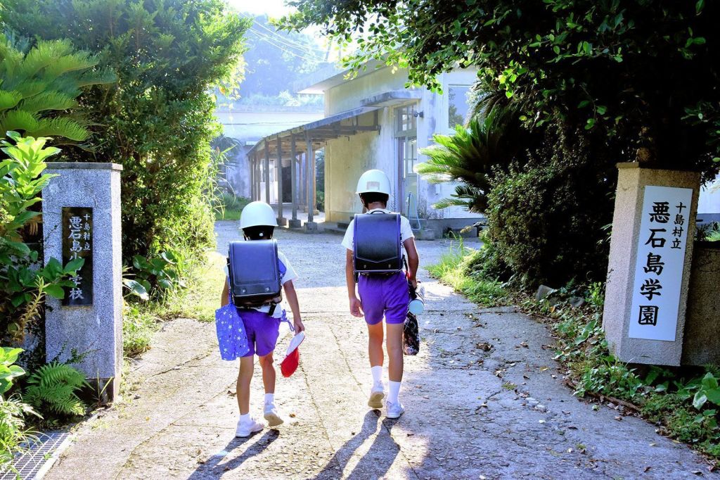 Alunos em Akusekijima, nas remotas Ilhas Tokara, no Japão, usando capacetes a caminho da aula em 30 de junho de 2025.