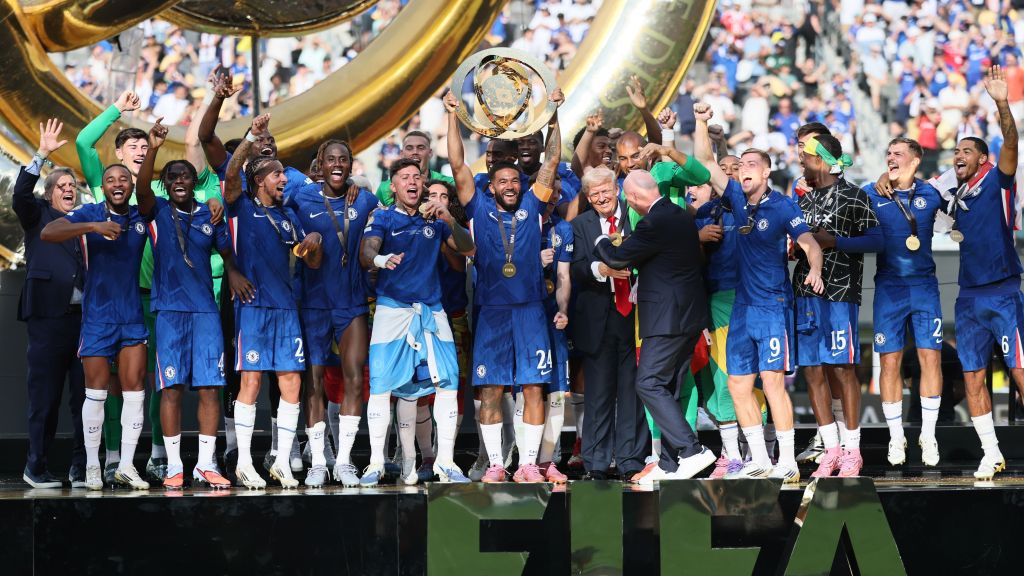 Gianni Infantino conversa com Donald Trump no pódio enquanto jogadores do Chelsea levantam a taça do Mundial de Clubes