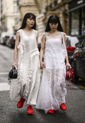 Guests are seen wearing white dresses Cecilie Bahnsen with red shoes outside Cecilie Bahnsen's parade during the Spring/Summer 2025 women's collection, as part of Paris Fashion Week, on September 25, 2024 in Paris, France • Daniel Zuchnik/Getty Images