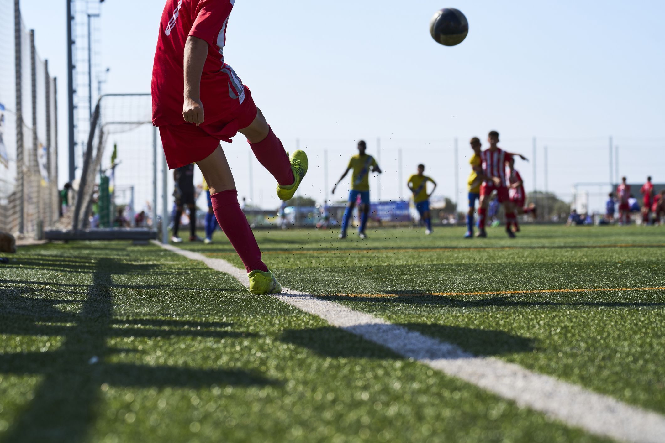 rear view of a boy in sportswear kicking the soccer ball with a corner kick for his team