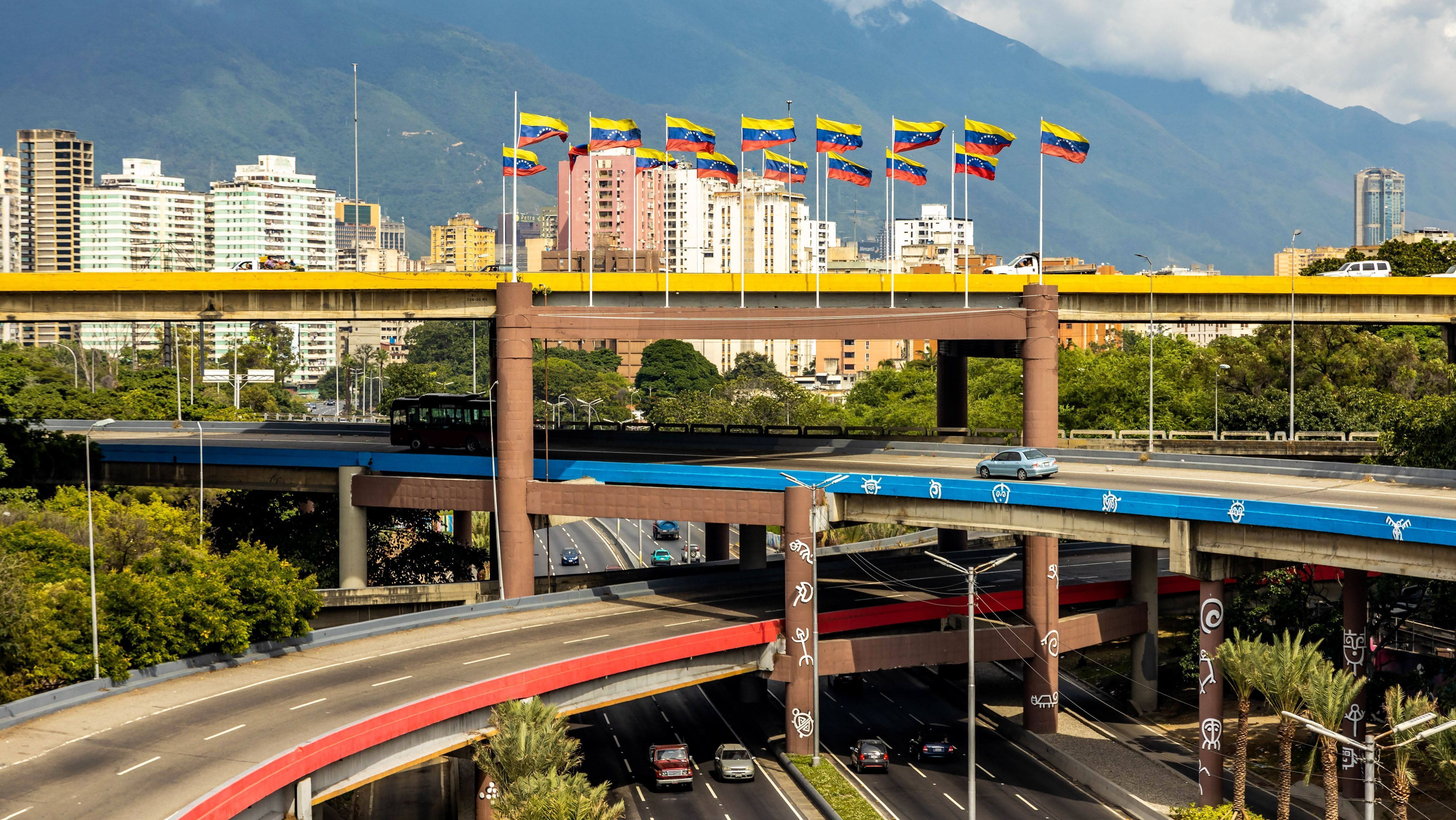 Rodovia de vários níveis no centro de Caracas, capital da Venezuela, com bandeiras nacionais hasteadas durante o dia