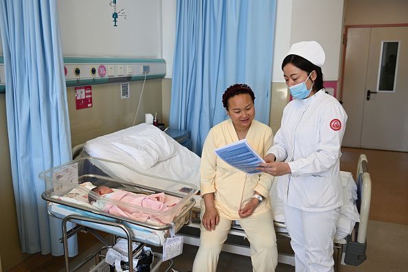 Uma profissional de saúde explica os subsídios locais para cuidados infantis em um hospital em Hohhot, na Mongólia Interior • China News Service/Getty Images via CNN Newsource