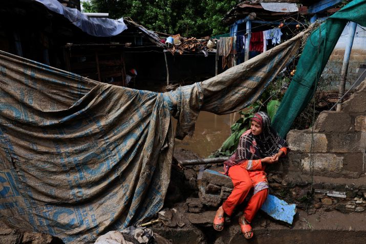 Menina sentada do lado de fora de casa, que foi danificada após fortes chuvas e inundações em Pacha Kalay Bazar, no distrito de Buner, Paquistão • Akhtar Soomro/Reuters via CNN Newsource